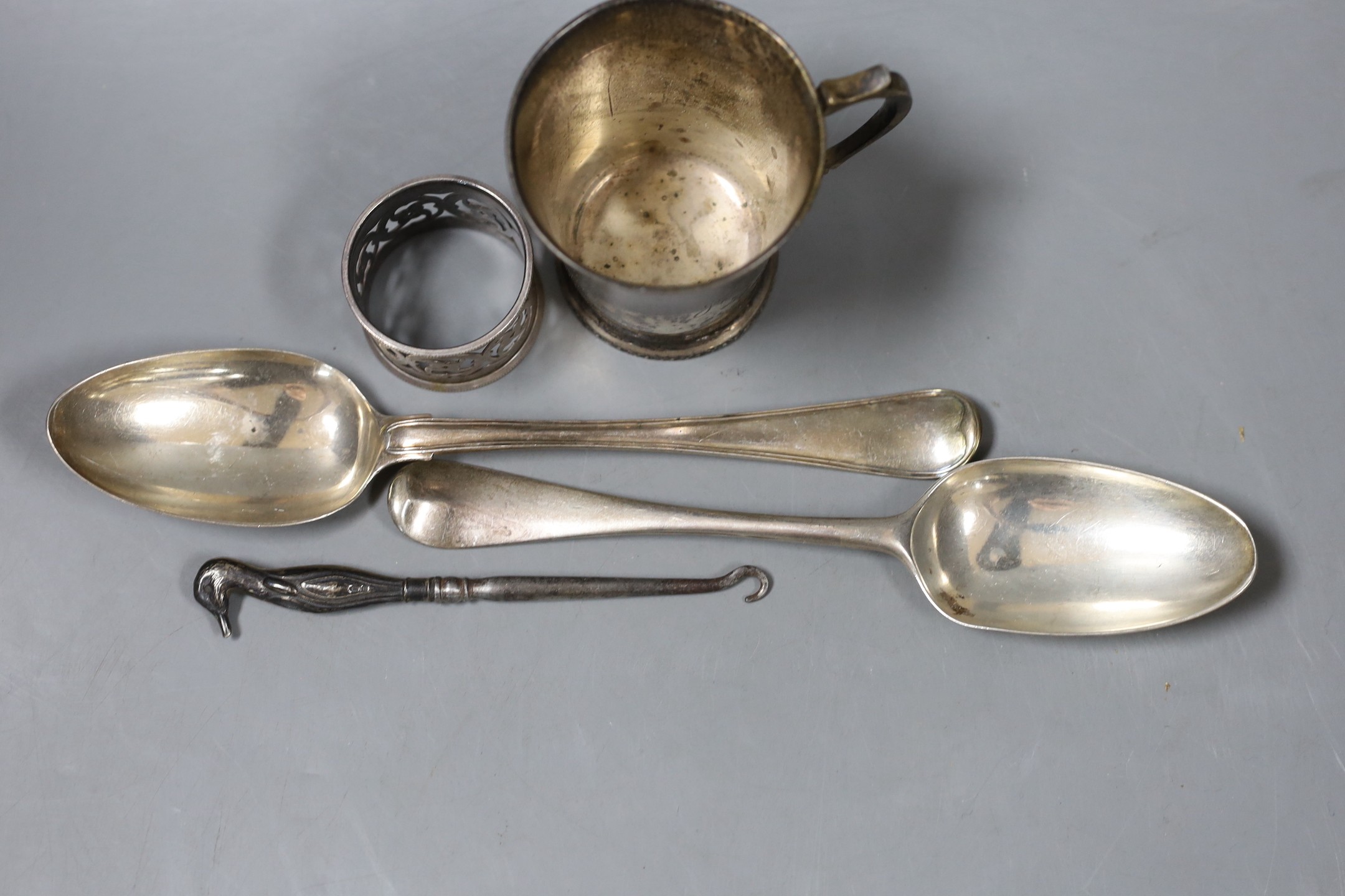 Two 18th century silver spoons, a later silver christening mug, small silver mounted heart shaped photograph frame, a silver napkin ring and a silver handled button hook.